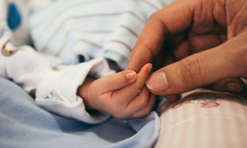 parent holding newborn's hand